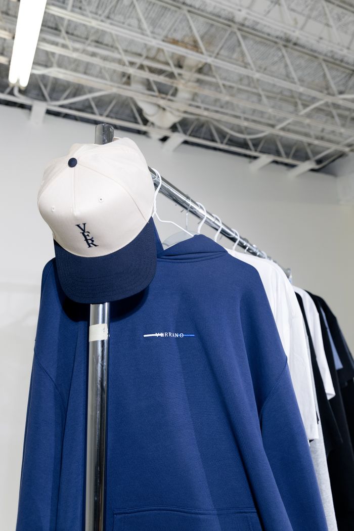Home Close-up of a clothing rack featuring a navy blue hoodie and a cap in a modern interior.